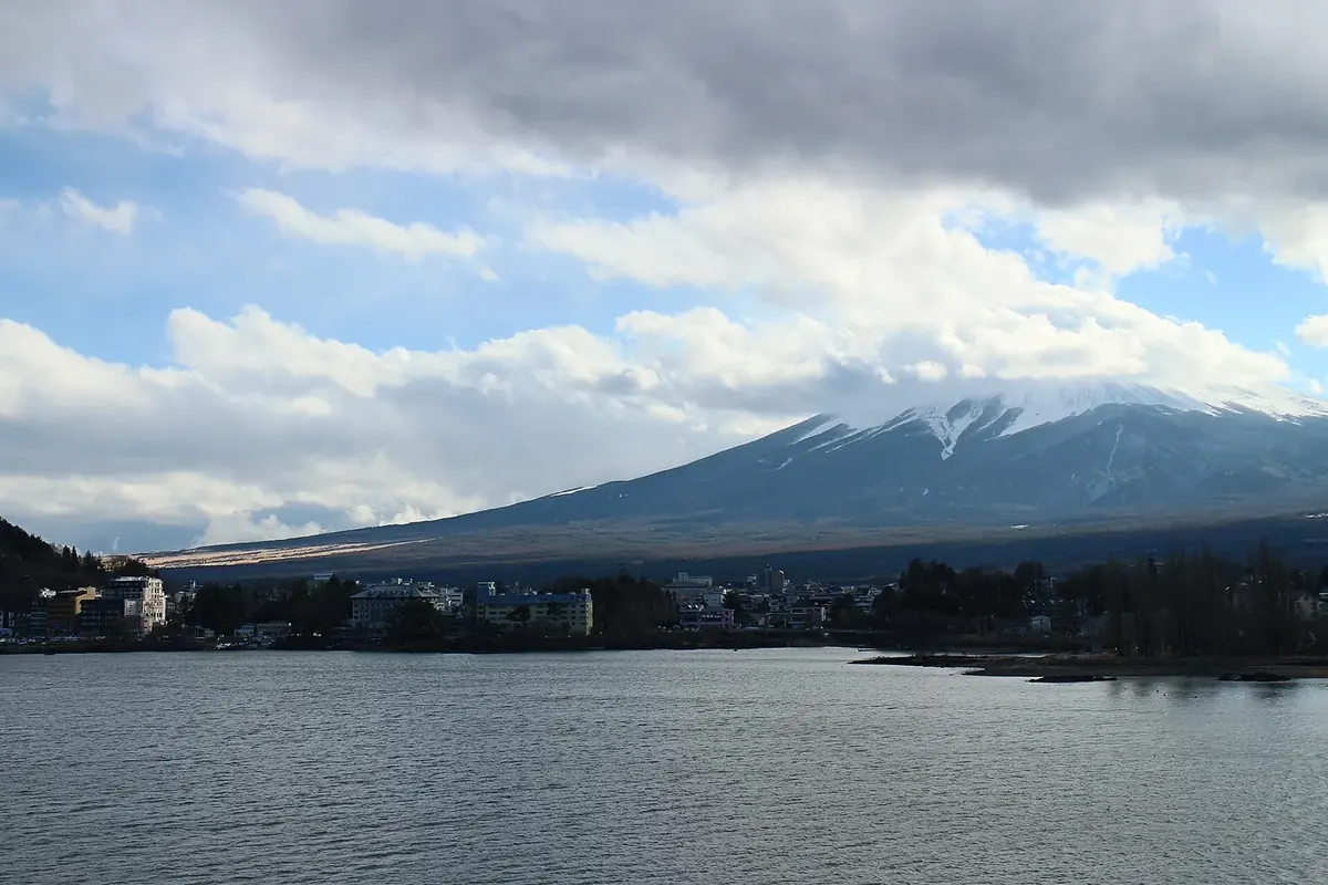 Mount Fuji beyond Lake Kawaguchiko under a partly cloudy sky